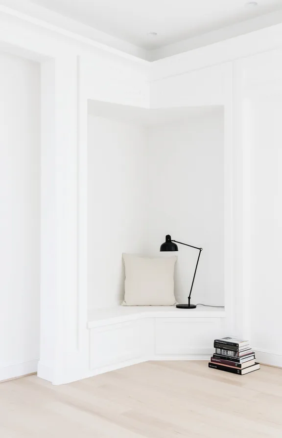 pure white walls and trim throughout, low white platform with single cream linen cushion