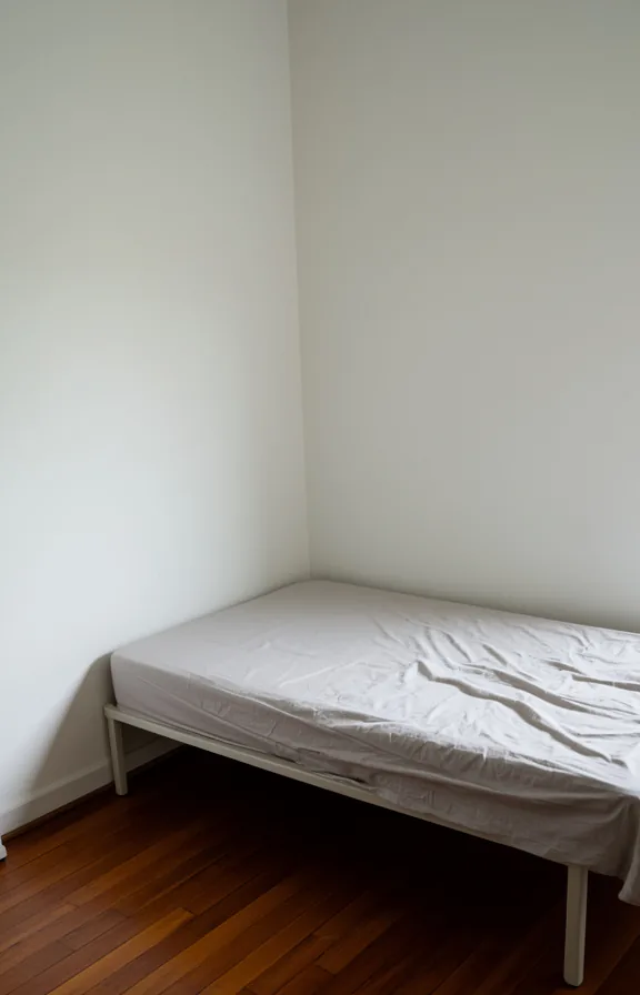 3/4 view of a sparse bedroom corner with plain white walls